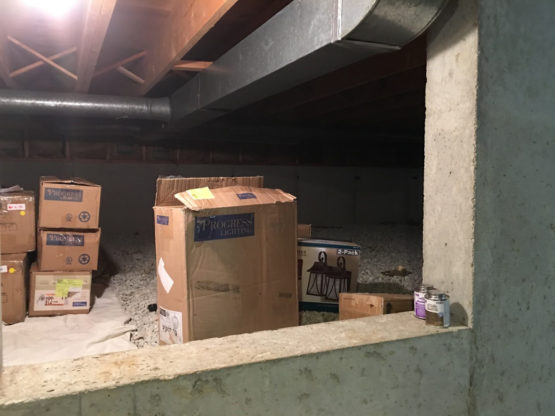 a damp crawl space in a Naperville, IL home full of boxes before crawl space encapsulation