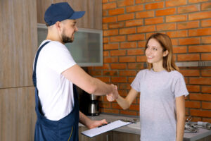 Working man in blue hat and overalls shaking woman's hand
